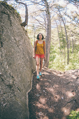 Naklejka premium The girl with a backpack is walking through the forest.