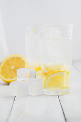 Lemon juice detox water. Mineral water infused with lemons. Wooden white table.