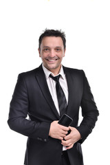 Young man wearing a a dark suit, white shirt and black tie, smiling holding a smart phone and a briefcase, isolated on white background.