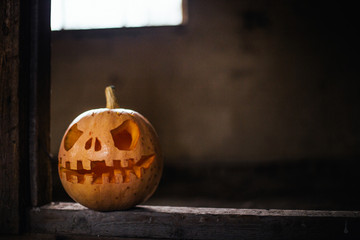 Halloween pumpkin in dark barn on wooden floor. Scary background for poster of celebration of Halloween.