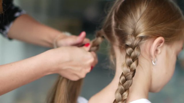 Mom Plaits the Braid Of Her Little Daughter