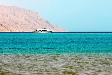 White ship in blue sea on mountain background in Red Sea