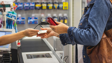 Woman holding a wallet and paying in a cash at shop. Check out in supermarket store. 
