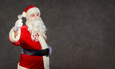 Santa Claus with a a  lamp on a Christmas copyspace background.
