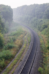 Fototapeta na wymiar Summer morning landscape. Empty railroad turn in sunrise mist