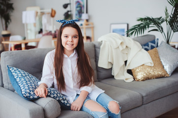 happy 10 years old kid or preteen girl relaxing at home. Cozy living room with modern scandinavian...