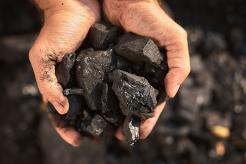 poor middle-aged man holding the hands of stone coal for sale to provide food for his family