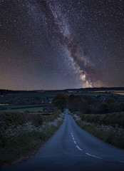 Vibrant Milky Way composite image over landscape of empty road in English countryside