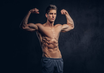 Fototapeta premium Handsome shirtless man with stylish hair and muscular ectomorph shows his biceps.