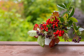 Bouquet of autumn berries and leaves in a pumpkin vase.Rowan berries, black chokeberry berries, viburnum in the basket.Copy space.Autumn gifts, harvest season.Copy space