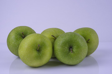 Five green granny smith apples on  white background and surface woth shadow. Side view.