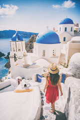 Travel destination europe tourist girl walking in Santorini at the three blue domes, famous Greek landmark. Oia village, Santorini island, luxury vacation. - obrazy, fototapety, plakaty