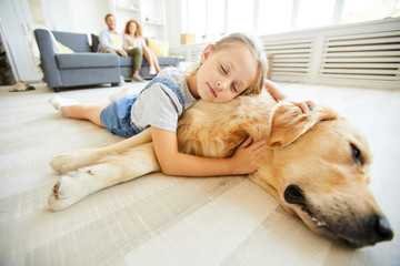 Cute little girl lying on her friendly purebred pet while both relaxing on the floor