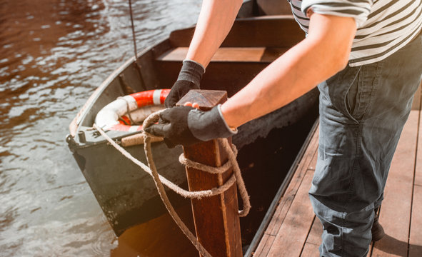 Man s hand with boat tiying rope. Sailor seaman gondolier Yachtsman moors his motor boat at jetty. Close up hands and bow of the boat european gondola.