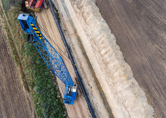 Pipelinebau - Rohre verlegen, riesiger Kran aus der Vogelperspektive