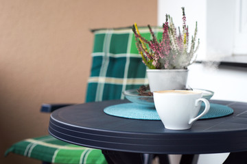 flowers next to cup of coffee on blue plastic table.