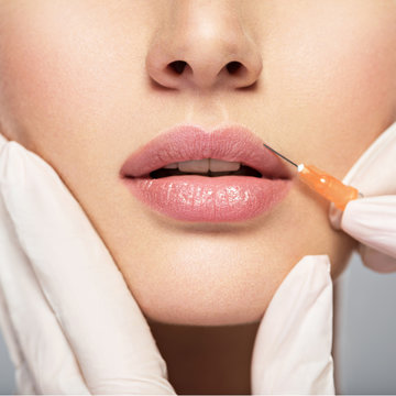young woman gets botox injection in her lips