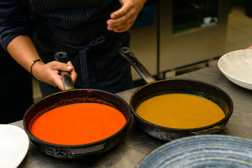 chef cook prepares a hot sauce in frying pan for a delicious meal in kitchen restaurant