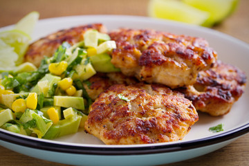 Homemade chicken patties or burgers with avocado corn salsa. horizontal