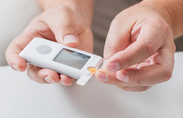 man measures sugar level with a glucometer