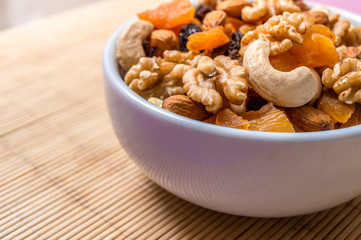 Mixed nuts and fruits in a white bowl