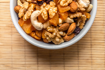 Fototapeta premium Mixed nuts and fruits in a white bowl