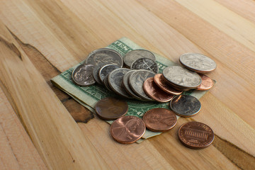 US Currency Cents on top of Dollar Bill on Wooden Table