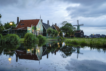 Night view of the De Huisman windmill with Dutch houses and reflection
