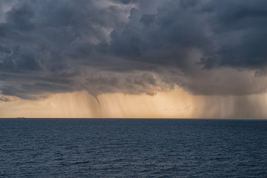 dense rain clouds and a tornado over the sea