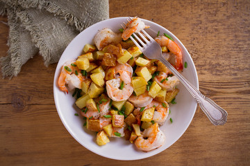 Shrimps with scallions and crispy potatoes in white bowl on wooden background. overhead, horizontal