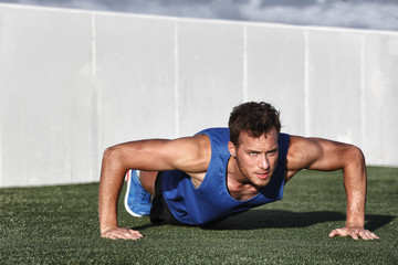 Sport fitness man push-ups. Male athlete exercising push up outside in sunny sunshine. Fit shirtless male fitness model in crossfit exercise outdoors. Healthy lifestyle concept.