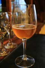 Vertical photo of a glass of amber color chilled craft beer on the dining table 