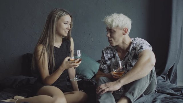 Young happy couple on romantic date drinking glass of wine at home