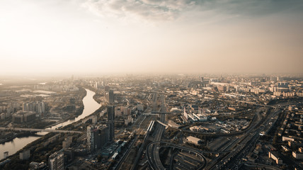 Fototapeta premium Panoramic Aerial View of Big City Moscow from above at twilight time, roads with car traffic, river and bridge, modern building