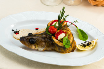 Trout with vegetables and caviar dressed with parmesan sauce on a plate