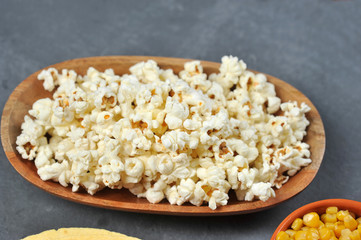 Popcorn in a wooden bowl.  Close-up. Gray background.