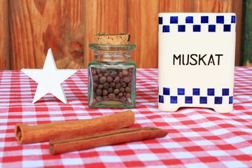 Vintage Behälter für Muskatnuss, Gläschen mit Piment, Zimtstangen auf karierter Tischdecke vor...