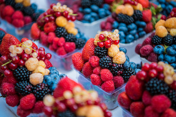 Fresh different berries in the plastic cup at Europe dong street berries and exotic fruits at market streetshop. Assortment festive appetizers in the cup, selective focus.