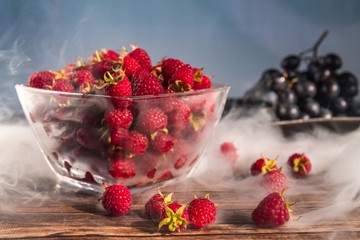 Delicious sweet raspberry berry in a glass bowl on a wooden rustic surface with copy space
