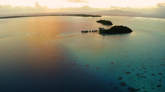 Aerial footage from a drone of luxury overwater villas during sunrise with yellow dramatic sky at Bora Bora island, Tahiti, French Polynesia, South Pacific Ocean (Bora Bora Aerial)
