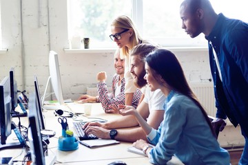 Fototapeta premium Creative office. Young modern colleagues in smart casual wear working while spending time in the office.