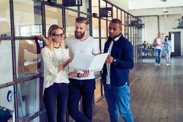 Sharing fresh ideas. Group of young business people in smart casual wear talking and smiling while standing in the office hallway.