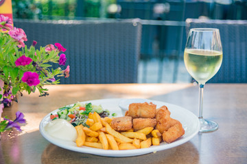 Close up shot of a french fries, fried chicken and white wine