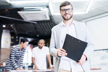 Portrait of young confident businessman leading his team at office