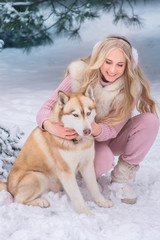 Mom and daughter walking a dog of the Husky breed in a snowy park