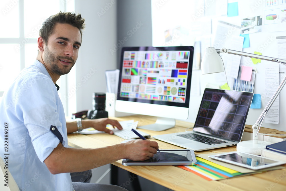 Aufkleber portrait of young designer sitting at graphic studio in front of laptop and computer while working o