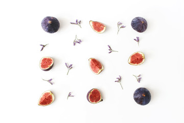 Fresh ripe purple figs. Food Photo. Creative composition of the whole and sliced exotic fruit and violet limonium flowers on a white table background. Floral pattern. Flat lay, view from above.
