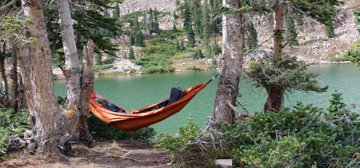 Backpacker Laying in a Hammock with a Mountain Lake in the Background © FreezeFrames