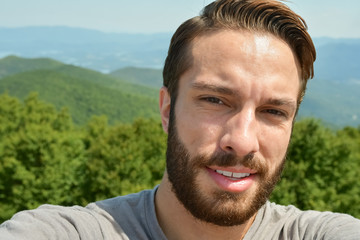 Fototapeta premium Man stands exhausted after a hike to the end of a trail