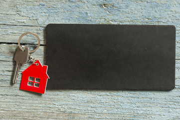 blank blackboard and symbol of the house with silver key on vintage wooden background